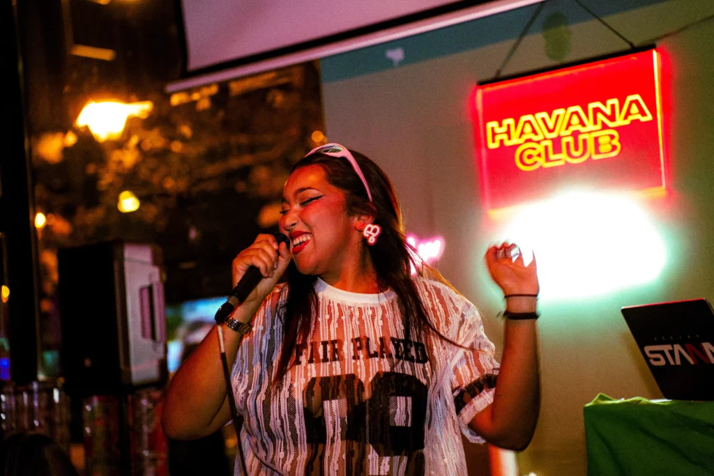NESS heureuse qui chante devant une pancarte HAVANA CLUB